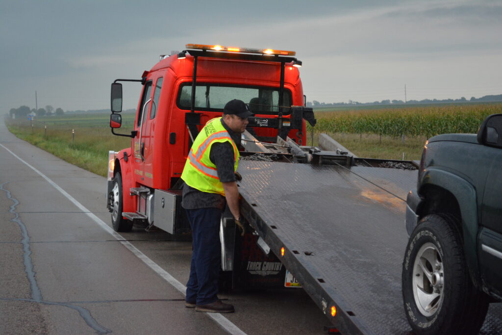 Tony's expert employee loading a vehicle onto a flatbed tow truck, showcasing efficient towing services in Northern Iowa.