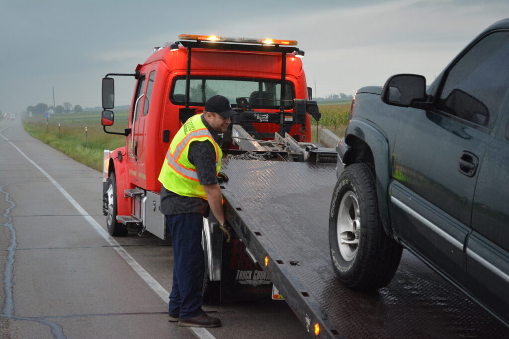 Tony's dedicated employee carefully loading a vehicle onto a flatbed for professional flatbed towing service in Northern Iowa.