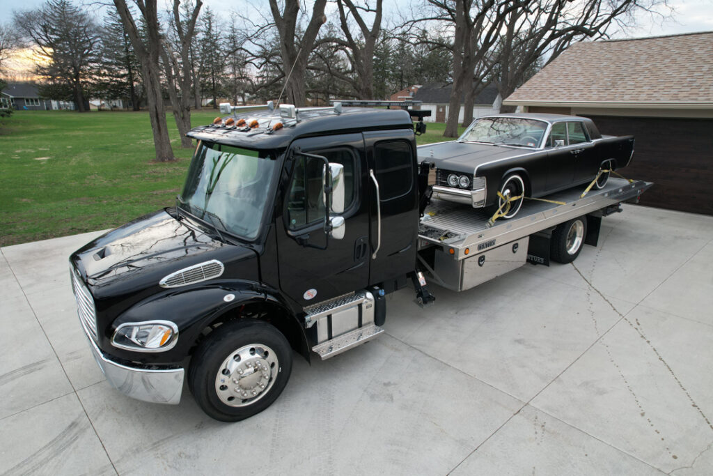 A classic car securely loaded on a flatbed tow truck by Tony's, ready for safe transport in Northern Iowa.